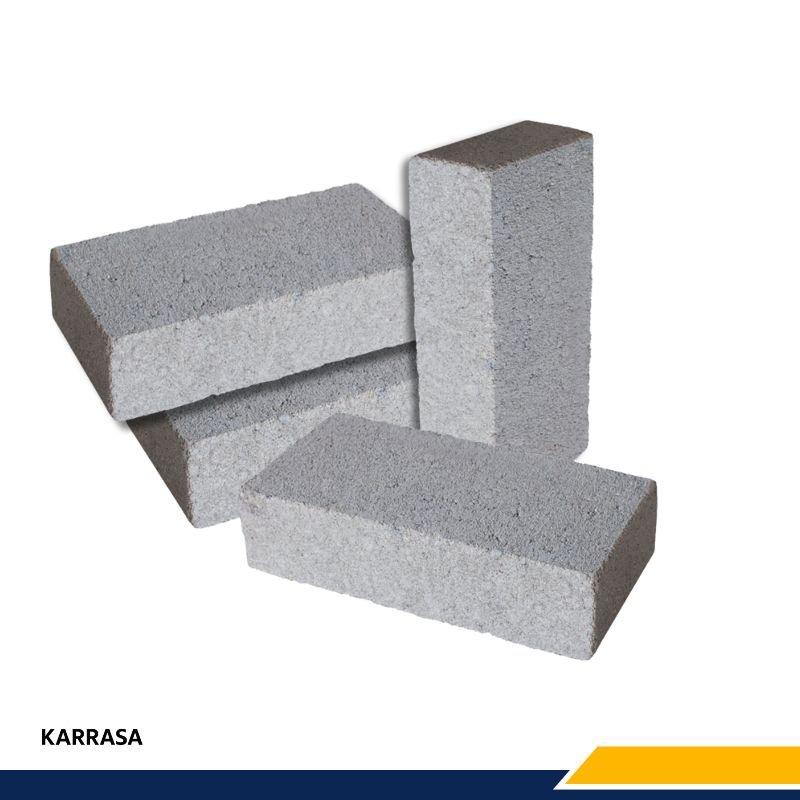 Tabiques grises de concreto apilados, marca Karrasa, para uso en construcción.