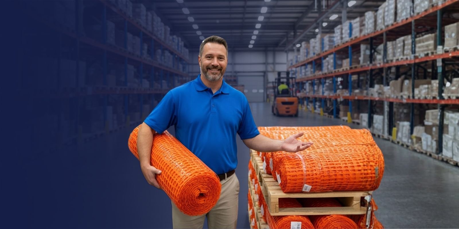 Asesor de Karrasa en un almacén, mostrando rollos de malla de seguridad naranja para delimitación de obras.